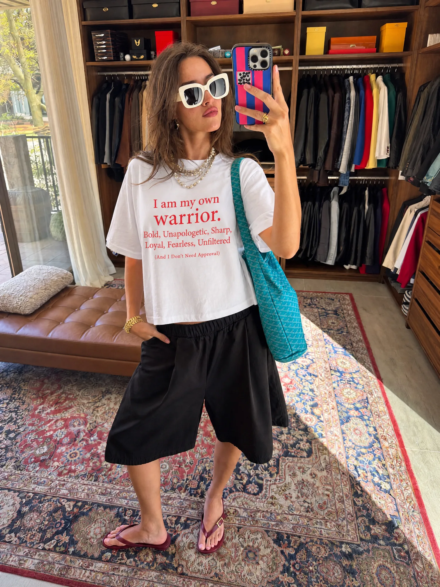 Mirror selfie of a model wearing a white graphic T-shirt with relaxed black shorts