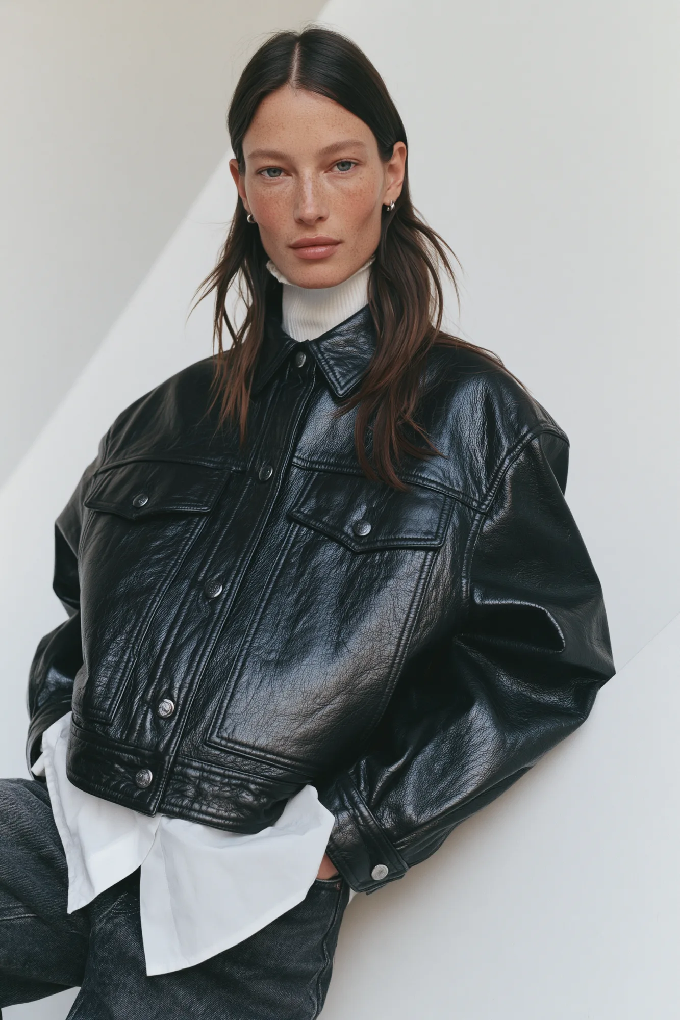 Portrait in a black leather jacket against folded white planes
