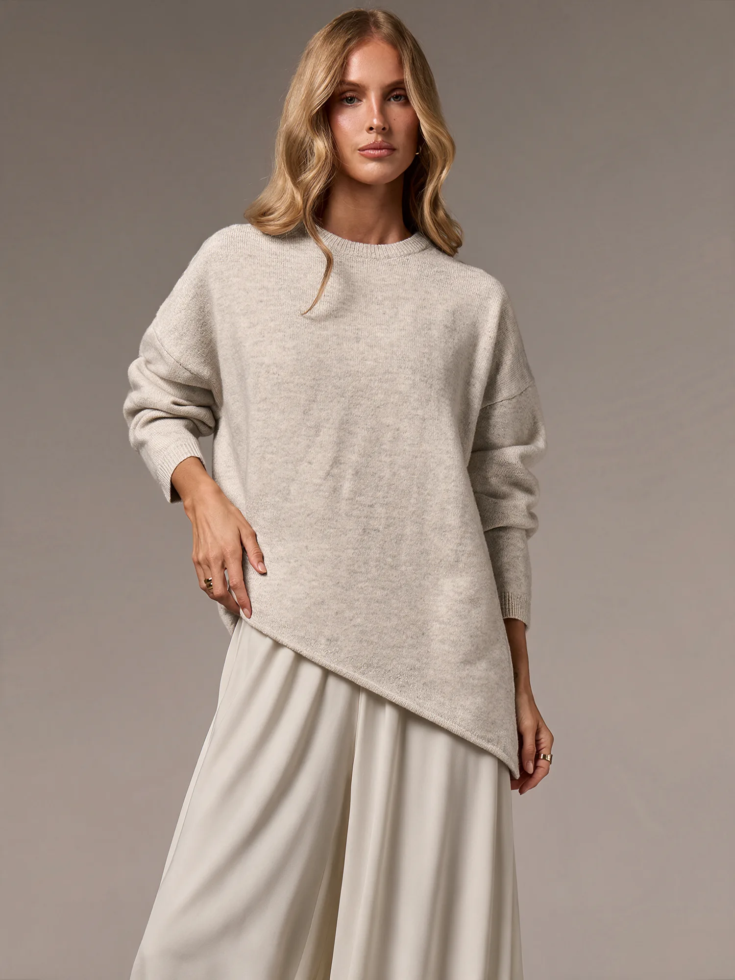 Model wearing an asymmetric light knit top and ivory skirt