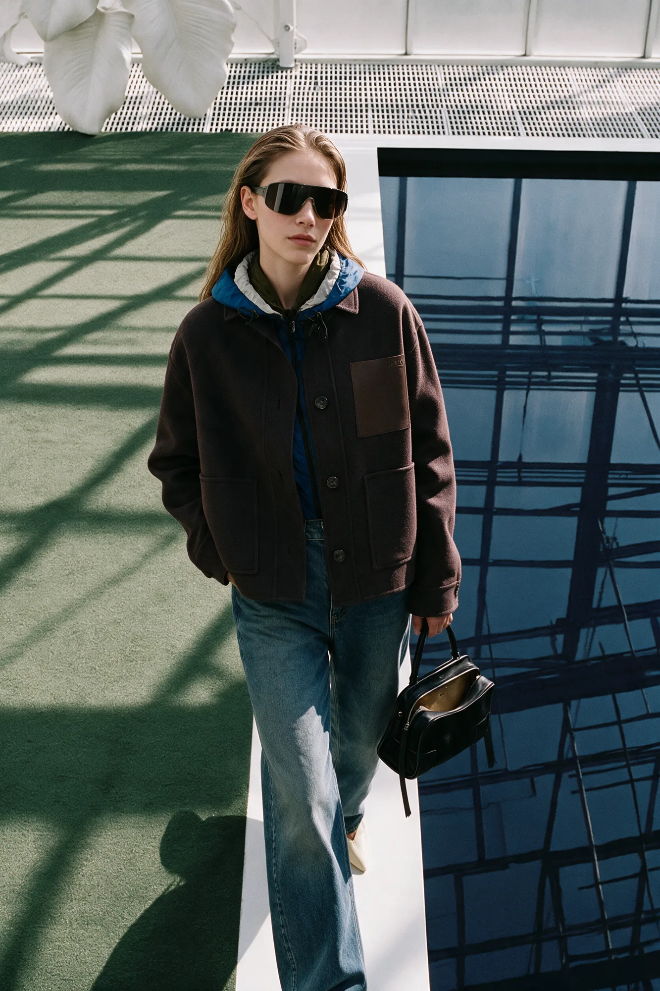 Model in navy tailoring beside greenhouse glass