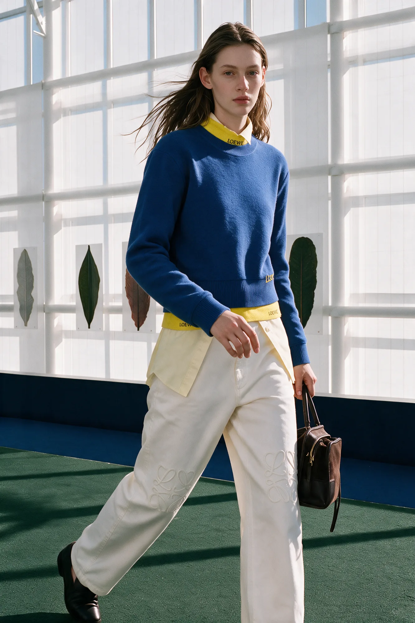 Model carrying a black bag above a greenhouse pool