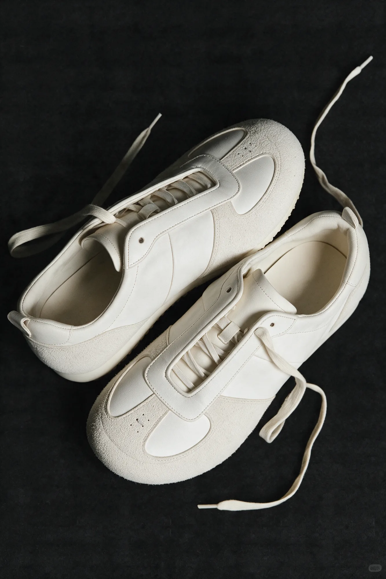 Pair of white trainers arranged on black fabric