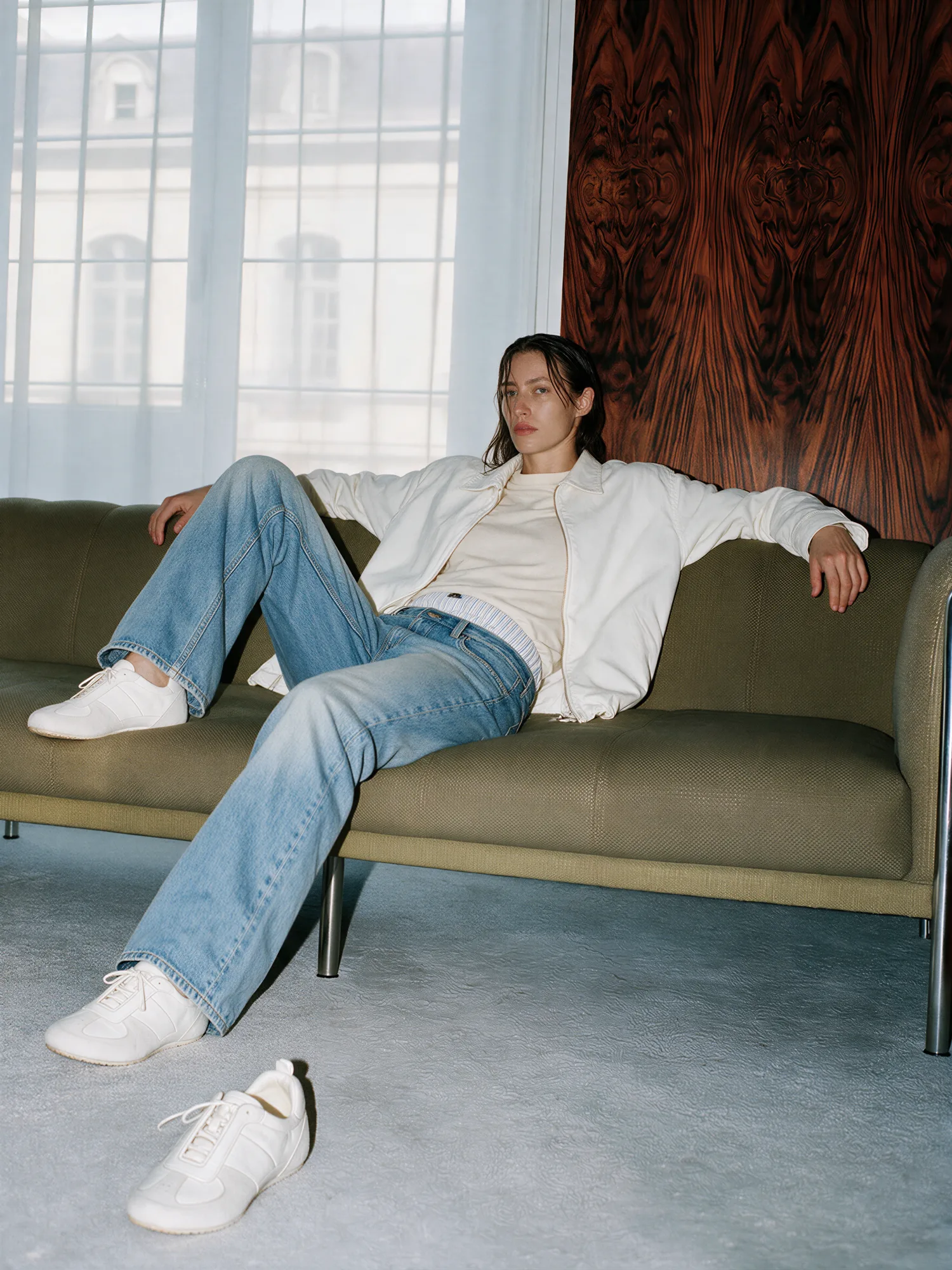 Model tying white trainers on an outdoor concrete step